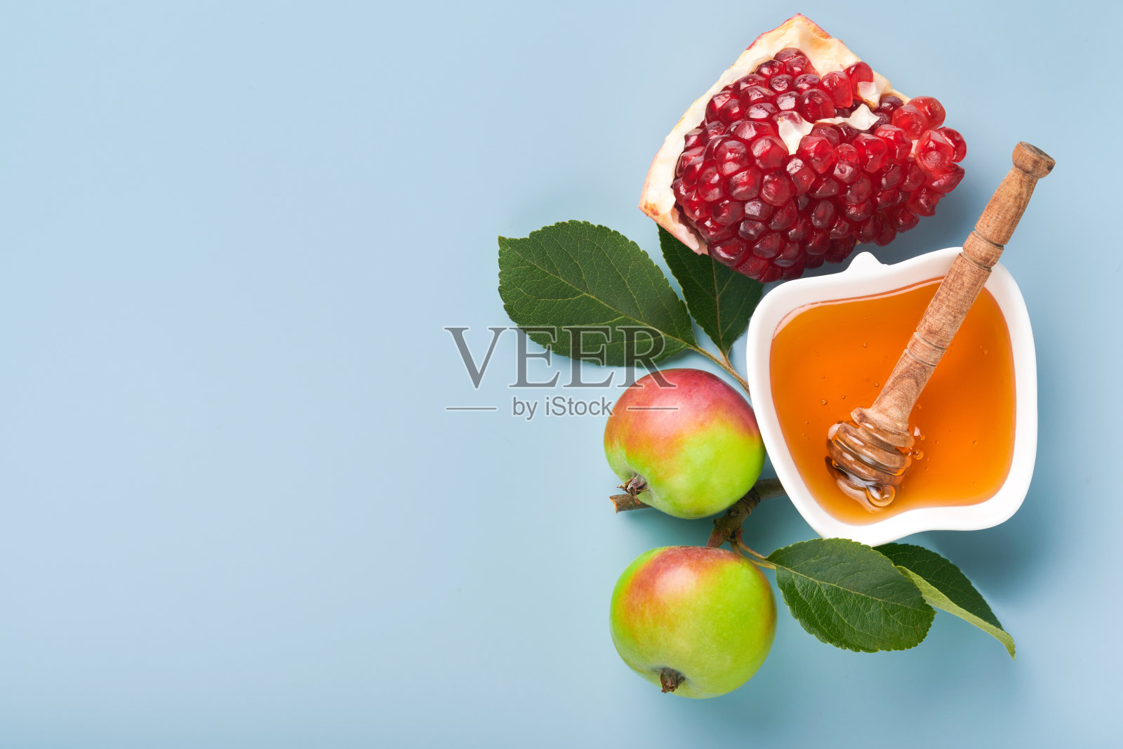 犹太新年。蜂蜜罐，蜂巢，苹果和石榴在简单的蓝色背景。犹太新年节日贺卡。犹太新年的节日属性。空间的文本照片摄影图片