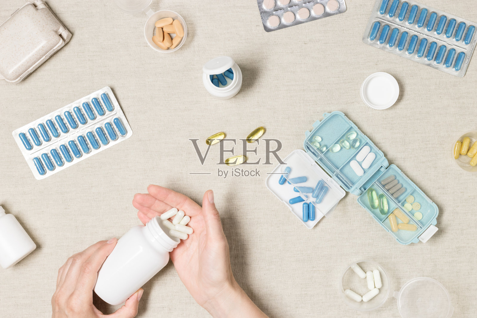 每日服药的药盒、片剂、胶囊。药盒内装有药丸，放在妇女手中的桌子上方，药物作为替代药物用于治疗和身体健康，平放。照片摄影图片