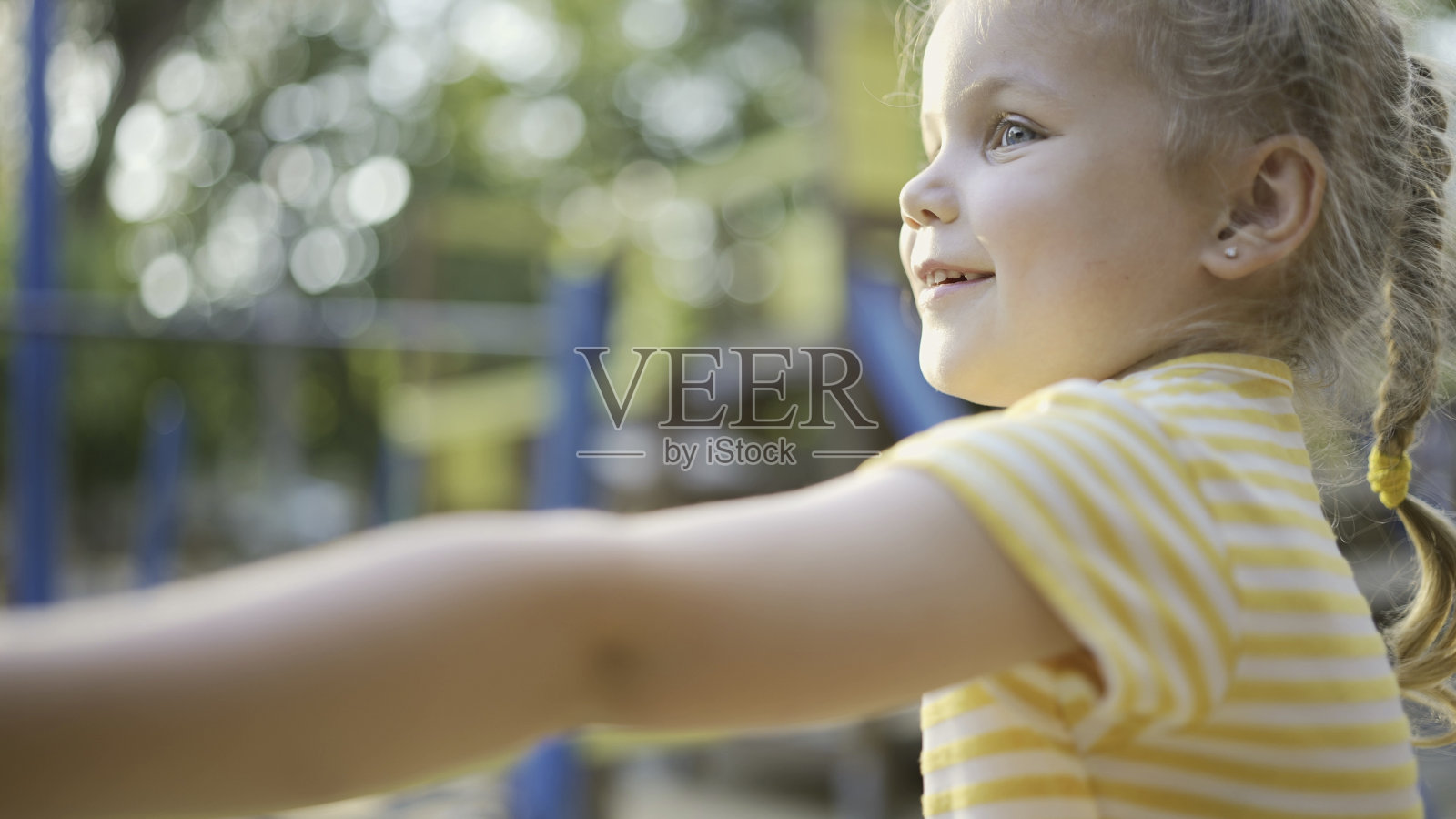 可爱的小女孩在操场上玩。一个小女孩在城市公园的操场上玩耍照片摄影图片