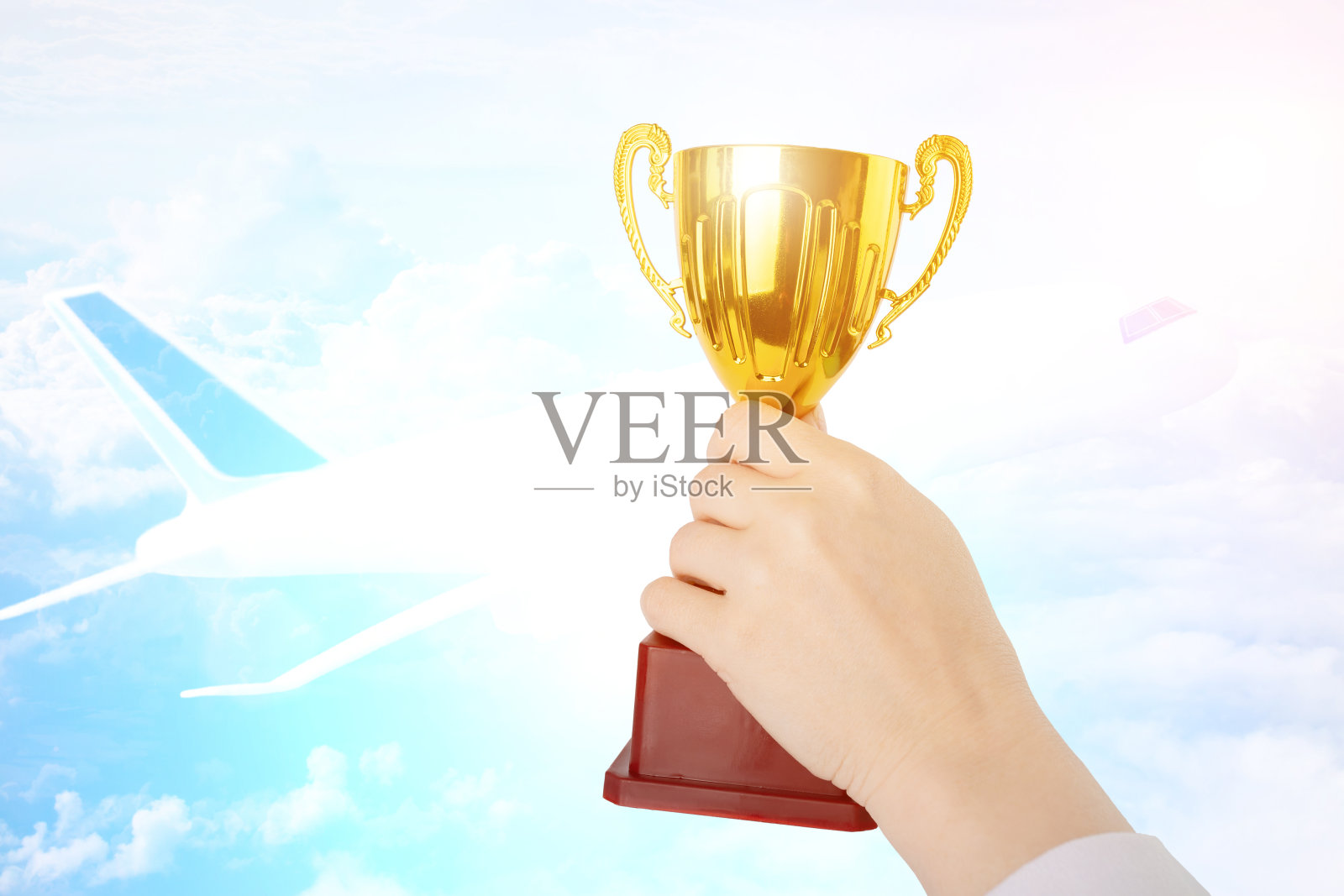 航空奖，金杯在手，背景是飞机在天空照片摄影图片