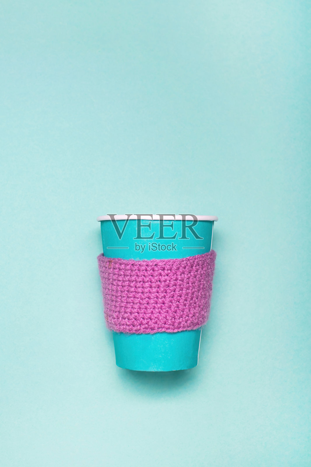 绿色背景的咖啡纸杯模型。舒适的咖啡纸杯搭配针织围巾。照片摄影图片