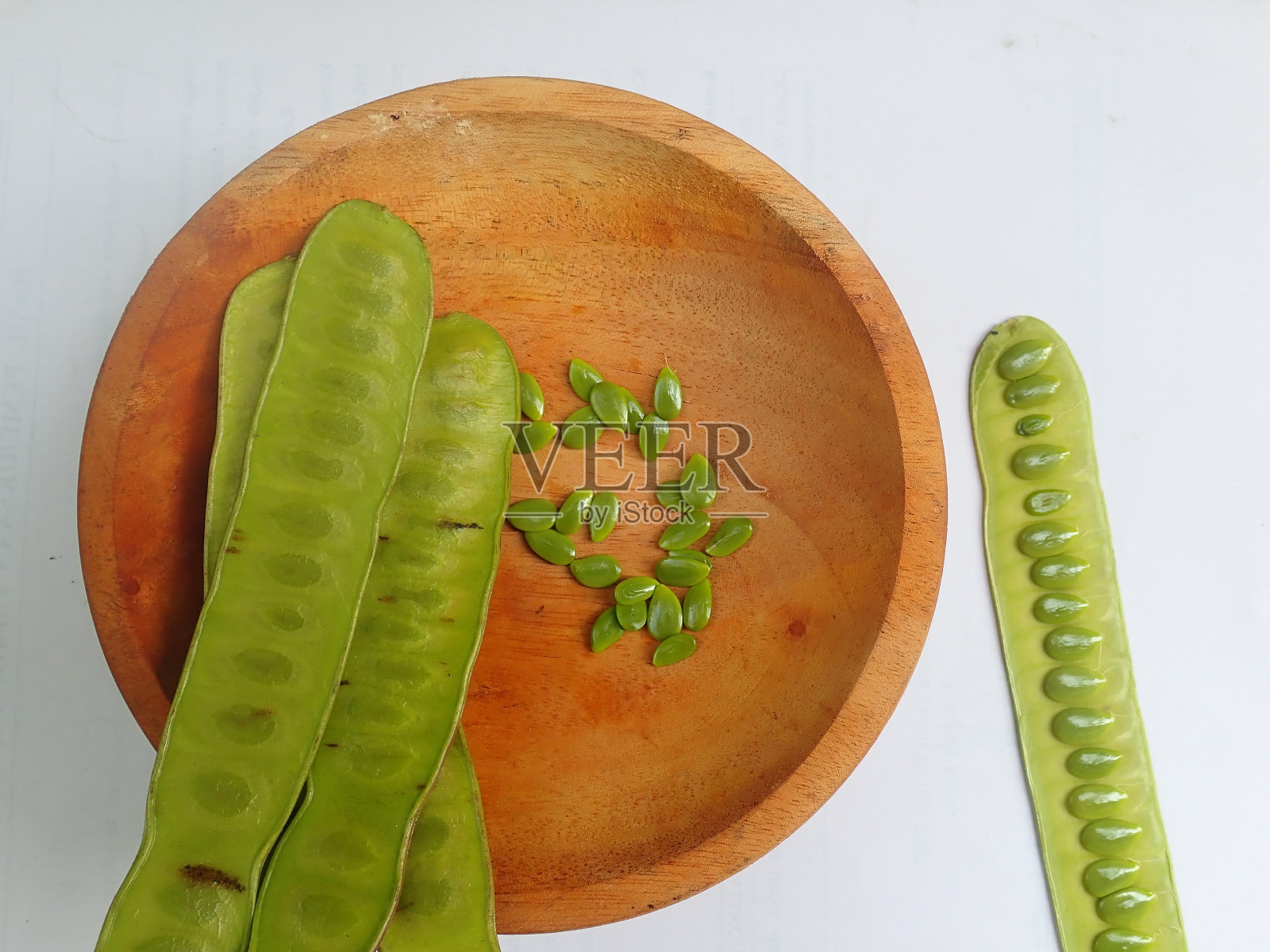 银合欢(lamtoro)在一个白色背景的木碗里。是豆科(豆科)的一种灌木。种子可以吃。照片摄影图片