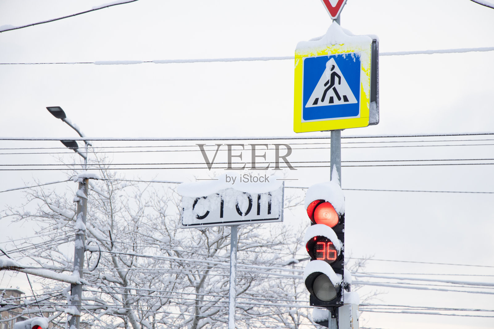 路牌上的人行横道冬天在下雪的城市里行驶，冬天在乌克兰第聂伯罗市有人行横道的路牌和红绿灯照片摄影图片
