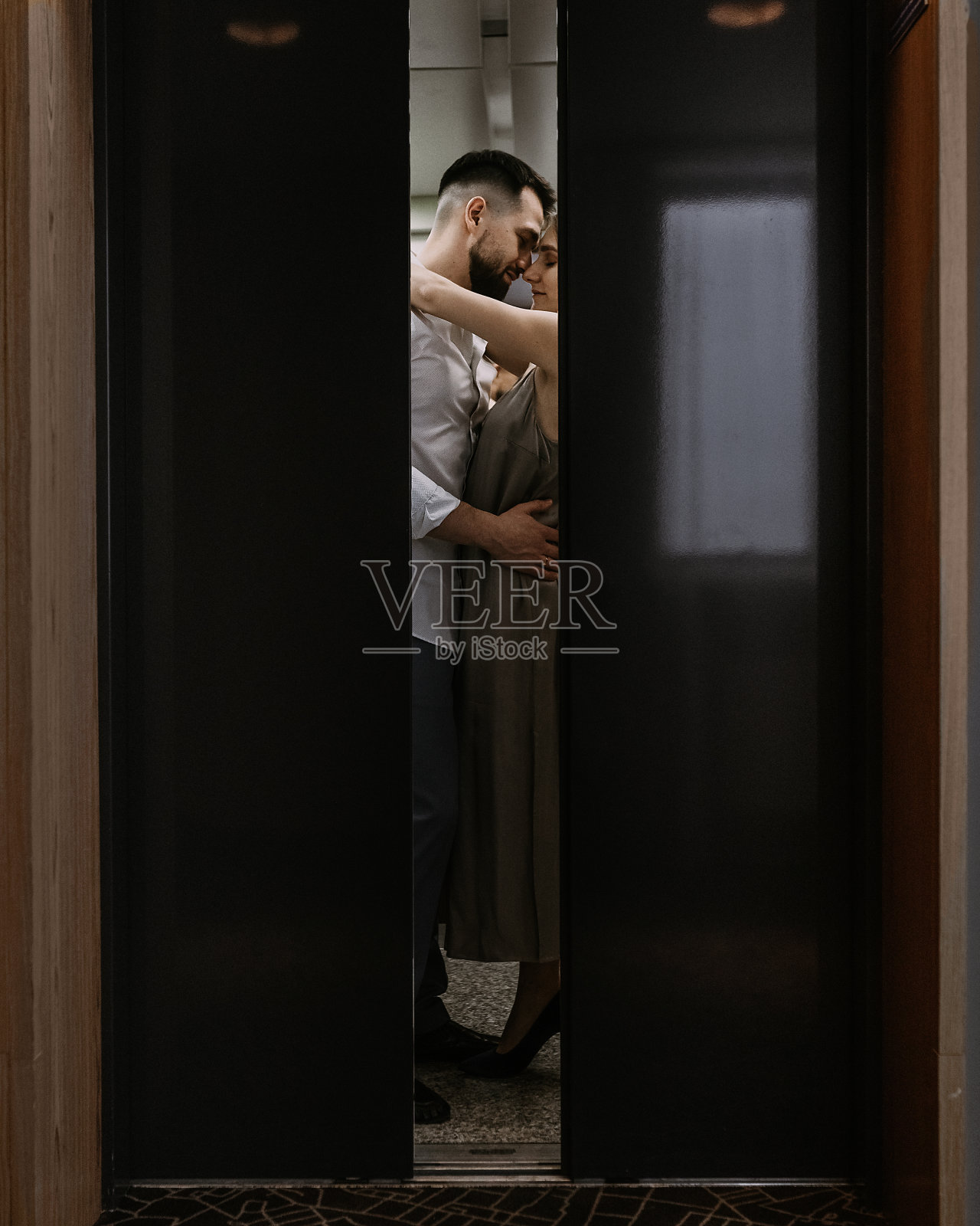 年轻时髦的白人夫妇在酒店电梯里拥抱亲吻照片摄影图片