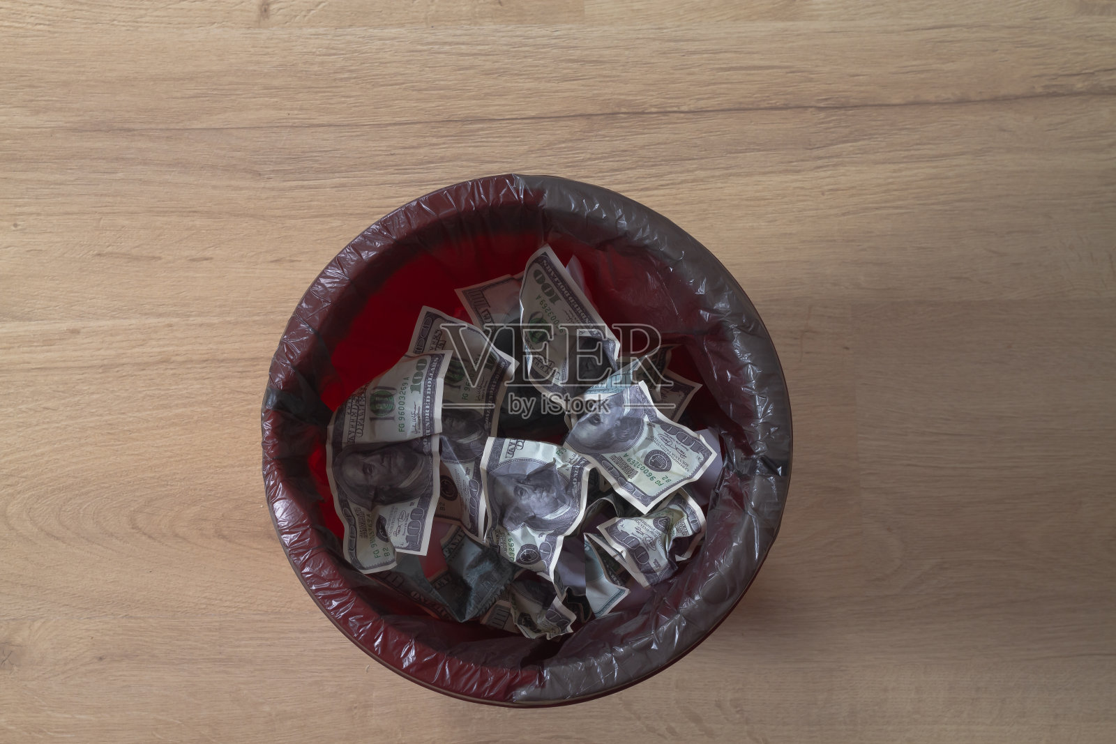 皱巴巴的假美元被扔进红色垃圾桶照片摄影图片