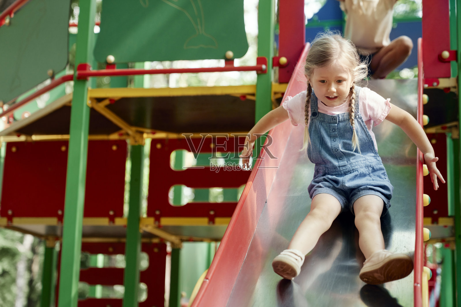 可爱的女孩在阳光明媚的日子里在操场上玩耍照片摄影图片