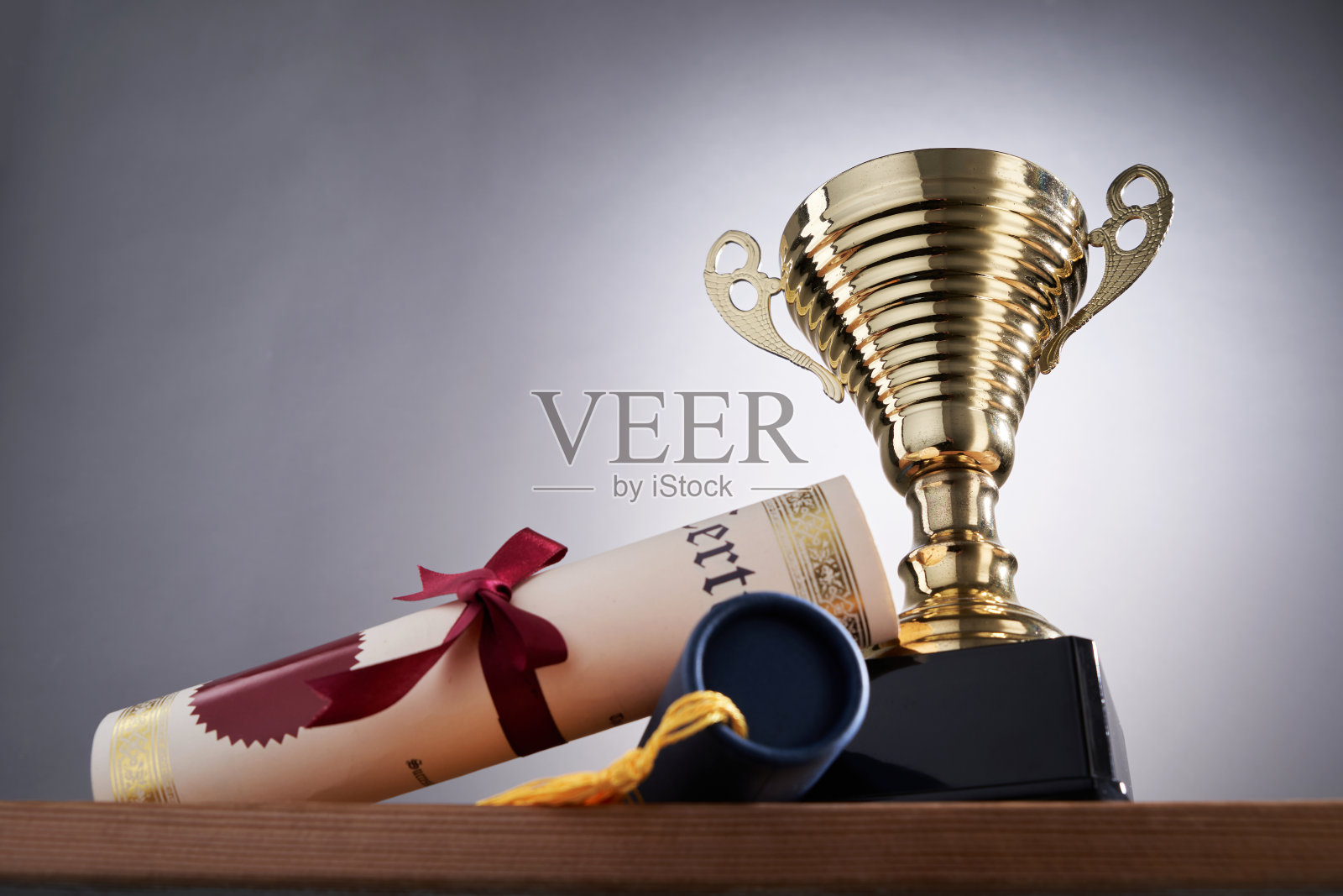 灰色背景下的金色奖杯和证书卷轴照片摄影图片