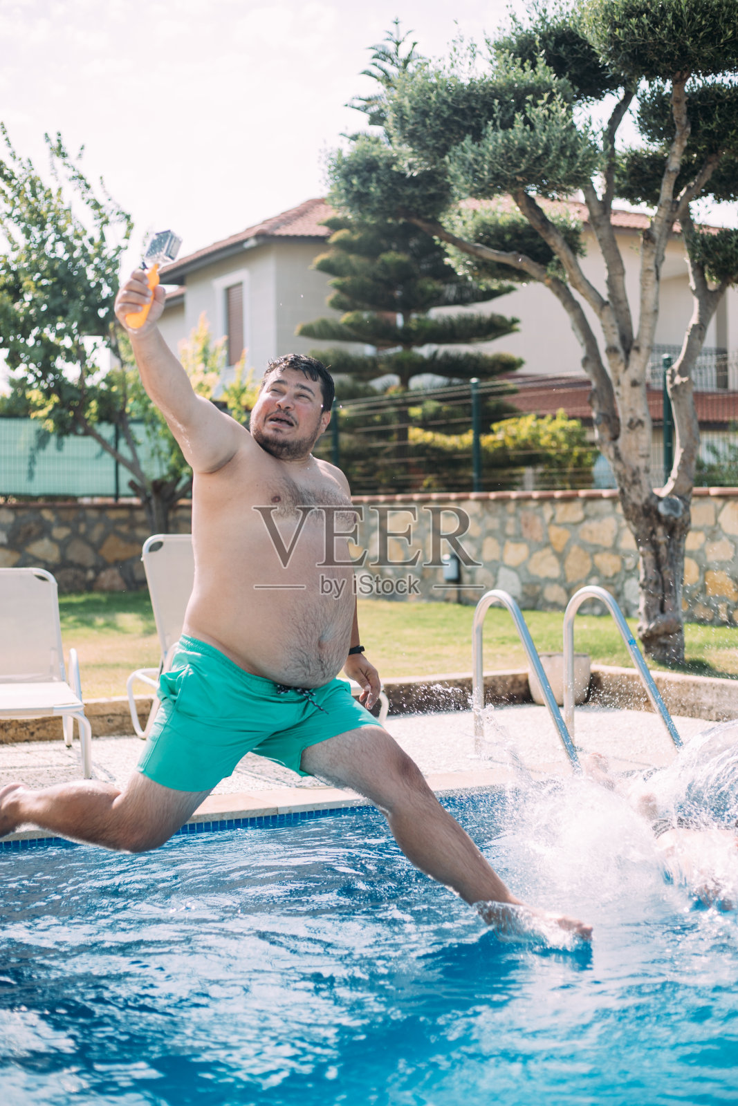 胖子带着摄像机跳进泳池照片摄影图片