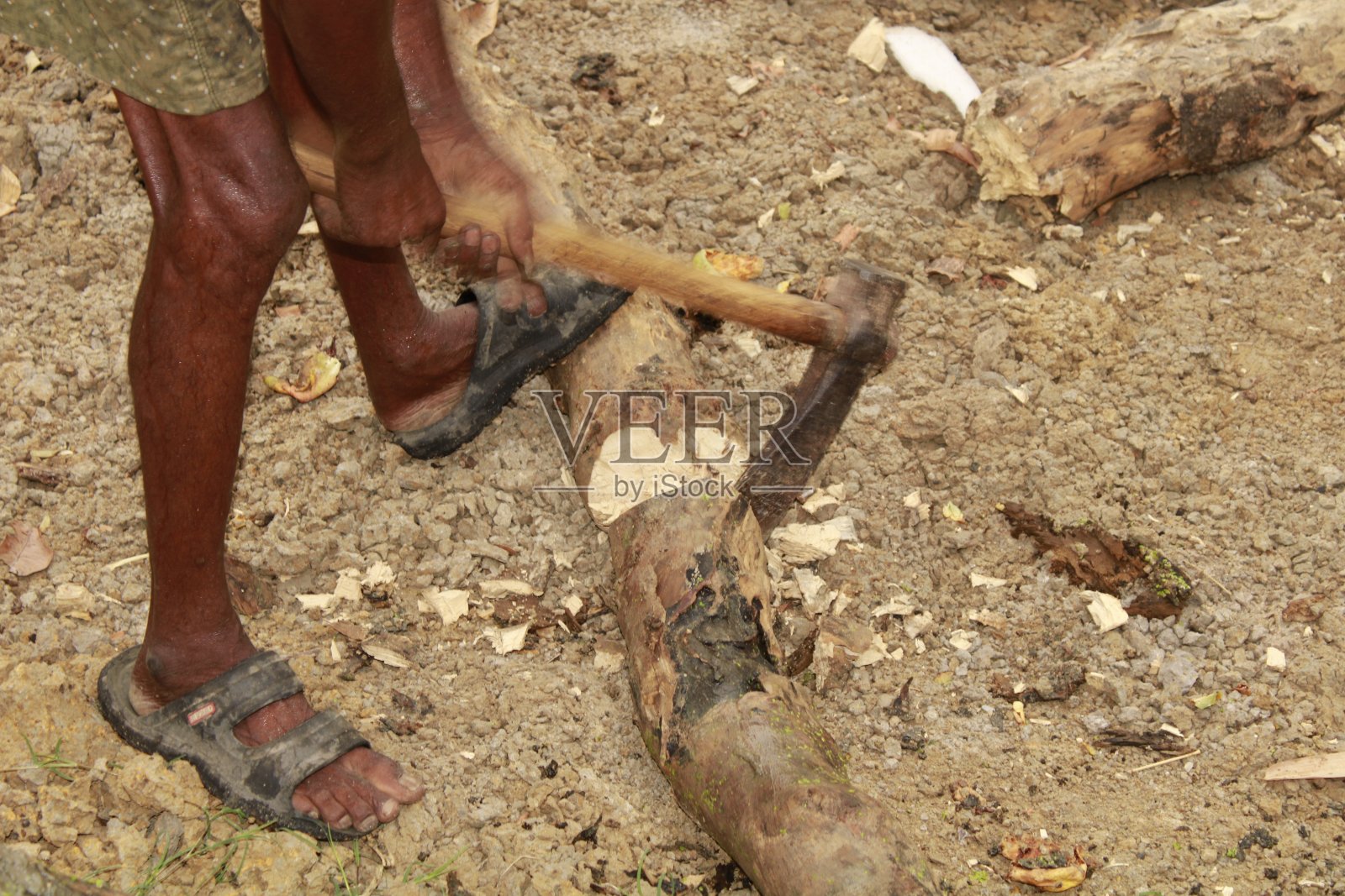 阳光灿烂的日子，印度中年体力劳动者用斧头砍柴。照片摄影图片