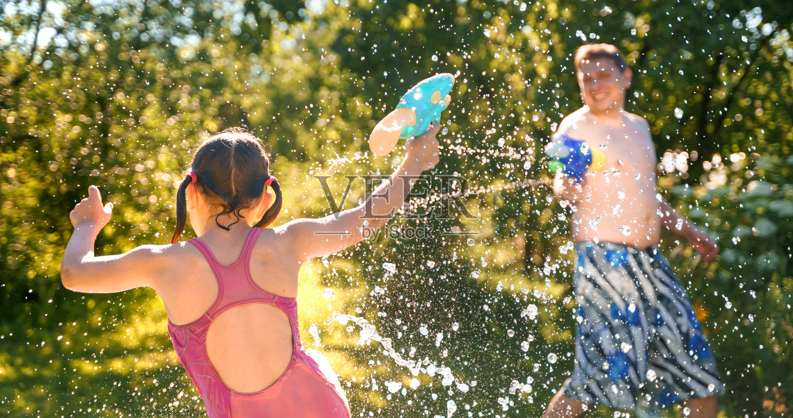 小女孩穿着泳衣，女儿爸爸，爸爸，爸爸游泳，玩水手枪，枪在孩子的充气游泳池在乡村别墅后院。夏天有趣的家庭户外游戏，娱乐消遣。居家旅游照片摄影图片