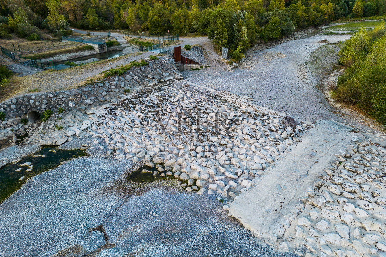 这条干涸的河流及其支流的河底清晰可见。越过一个小瀑布。可见的石头和水残留物。航拍-背景照片摄影图片