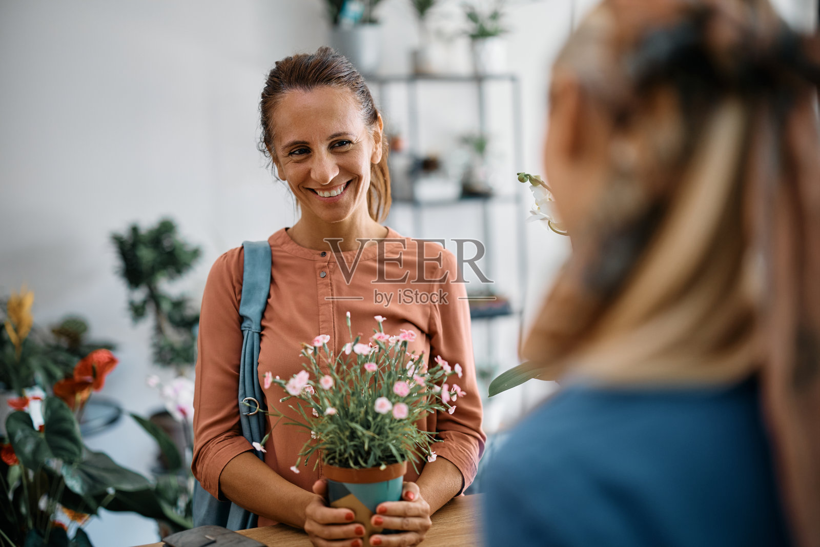 快乐女人买花，并与花店花匠交流。照片摄影图片