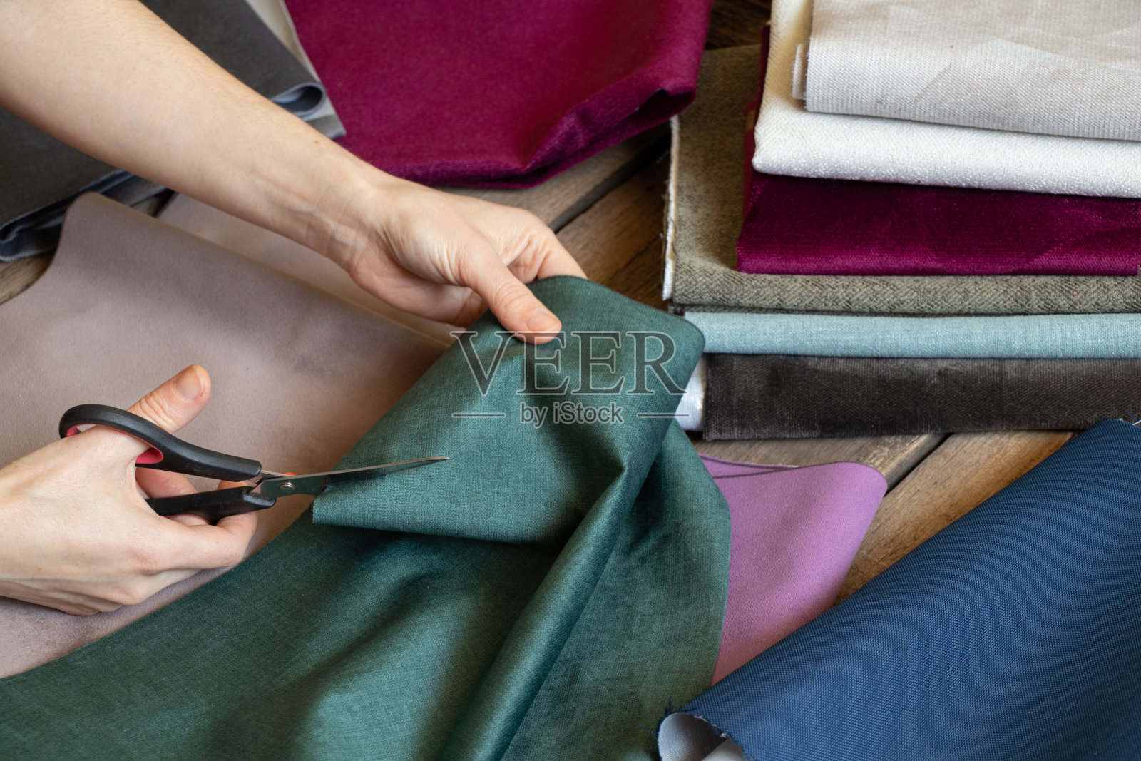 女人们用手在桌子上剪出不同的布料，裁缝工坊，缝纫时尚照片摄影图片