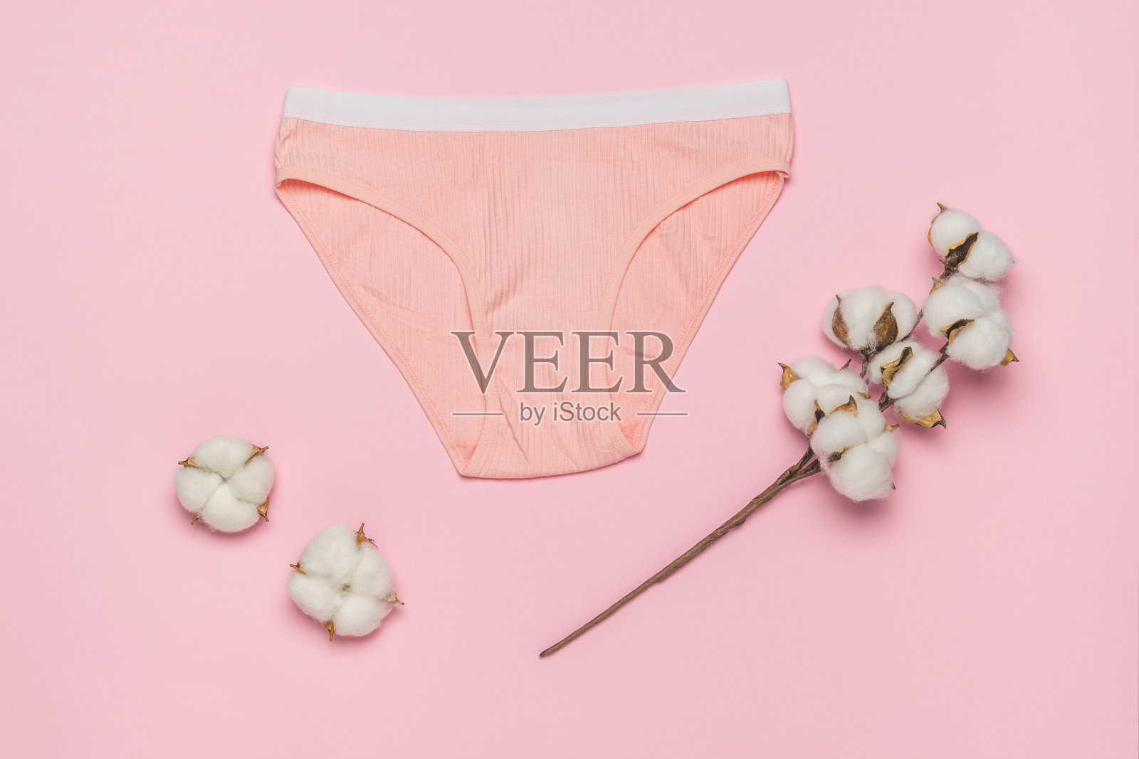 橙色内裤，白色条纹，橙色背景上有一小枝棉花。女性内衣的最小概念。照片摄影图片