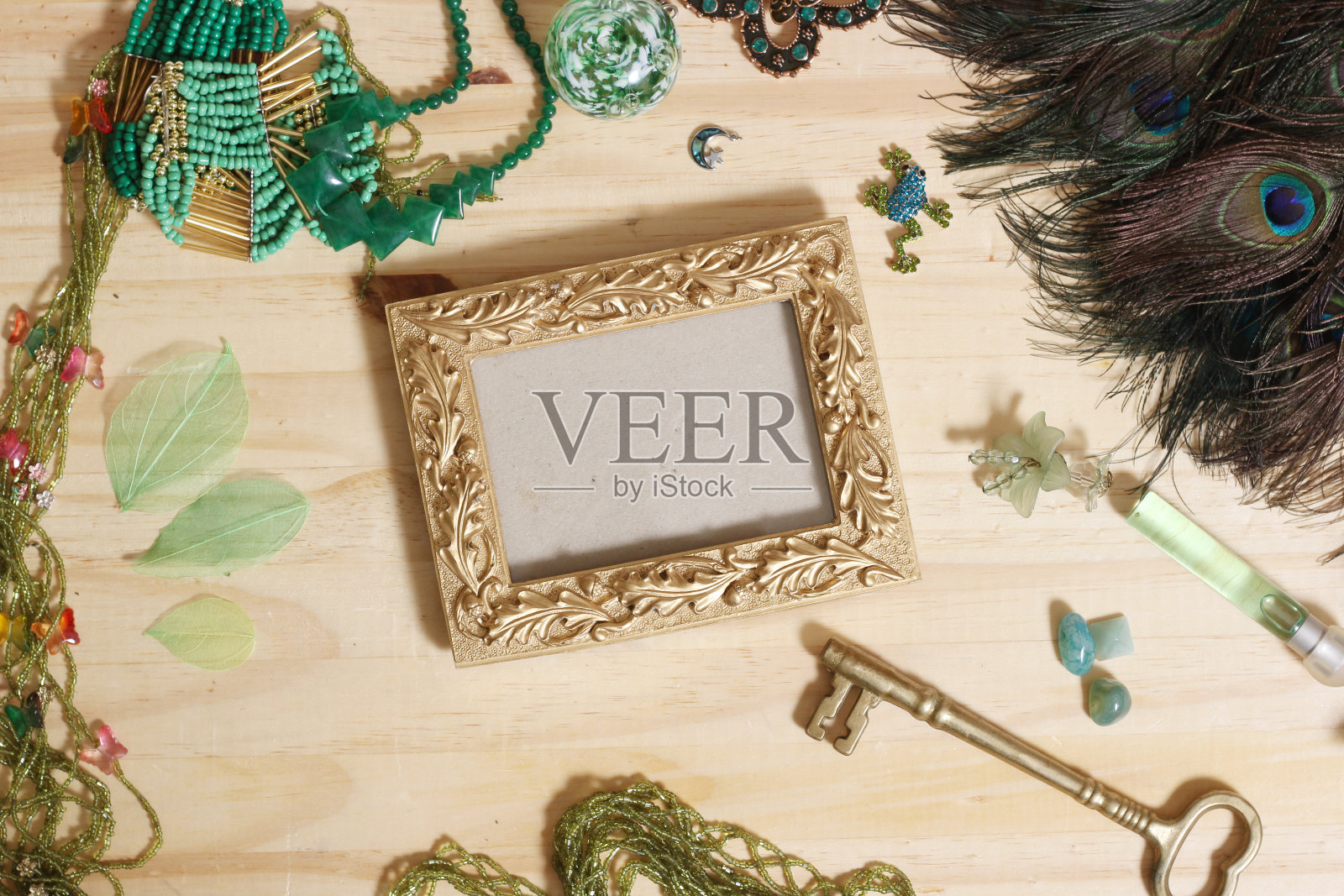 绿色珠宝和孔雀羽毛与金画框木桌照片摄影图片
