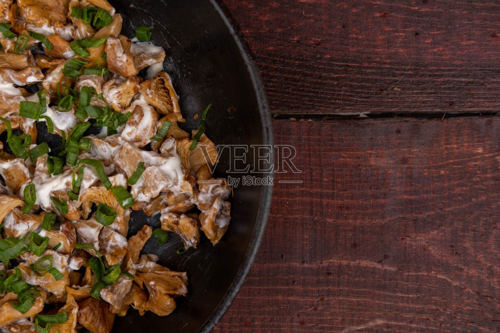 法式炸鸡油菌、洋葱和酸奶油放在平底锅里，深色木质背景上，大蒜、洋葱、欧芹和莳萝绿叶菜相互摆放。照片摄影图片