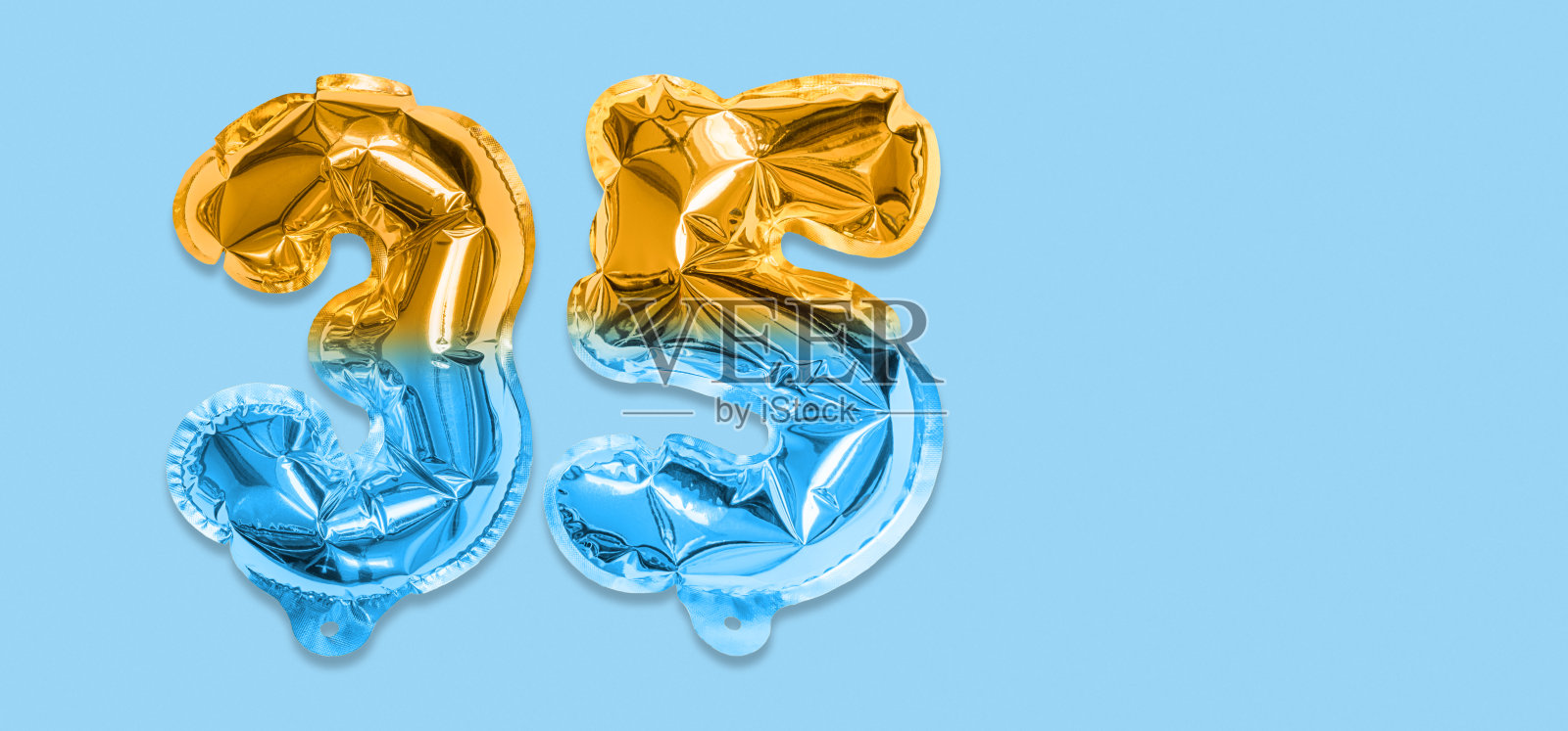 彩虹箔气球号码，数字三十五在蓝色的背景。印有35字的生日贺卡。照片摄影图片