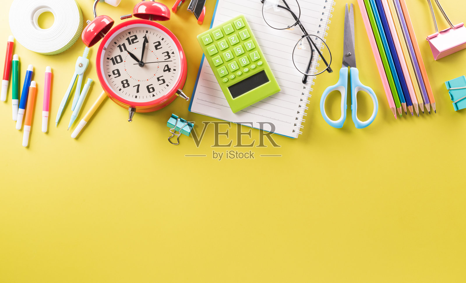 教育还是返校的概念。彩色学校用品的顶部视图与书籍，彩色铅笔，计算器，钢笔剪夹和苹果在粉彩纸的背景。照片摄影图片