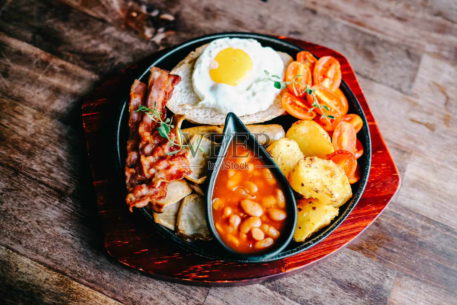 美味的英式早餐，有煎蛋，豆子，培根和烤土豆。照片摄影图片