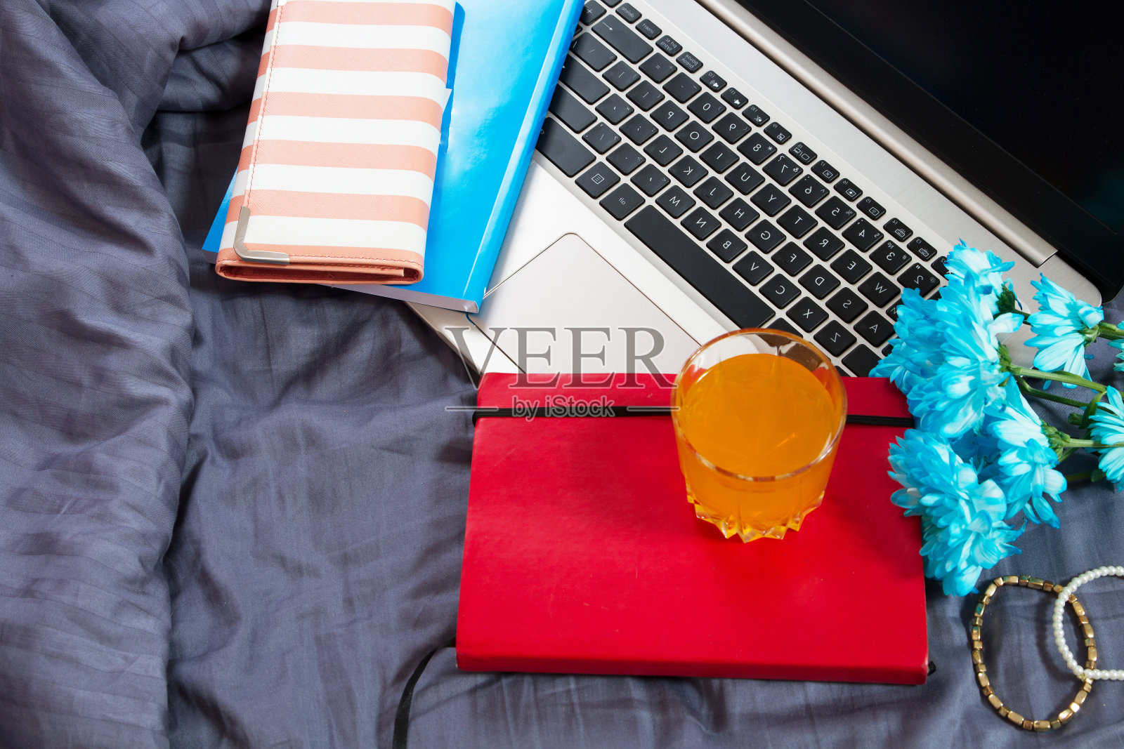 手，电脑键盘，床上视图。工作背景，在家工作，笔记本和鲜花照片摄影图片
