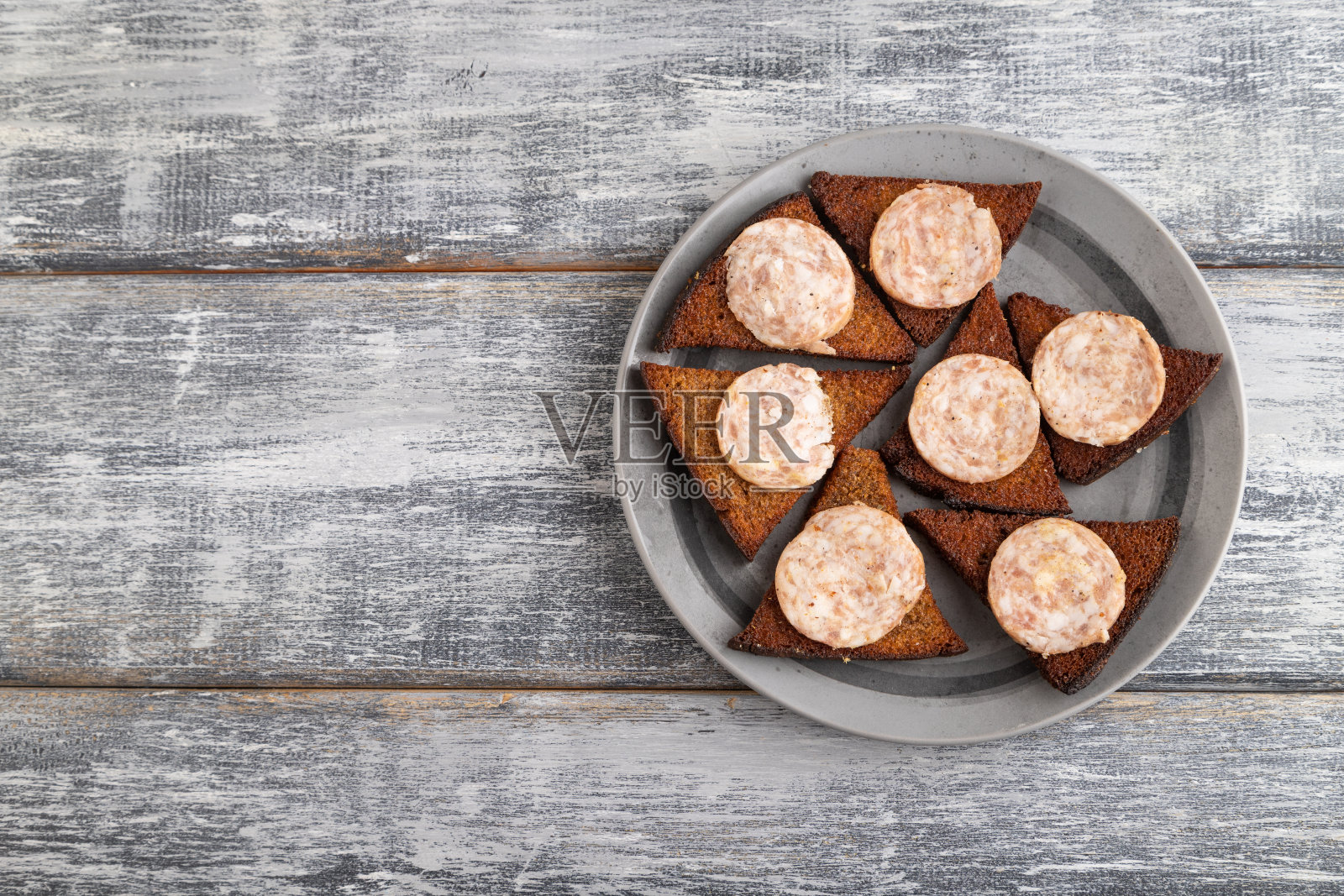 灰色木制背景的灰色盘子里放着香肠和吐司。俯视图，复制空间。照片摄影图片
