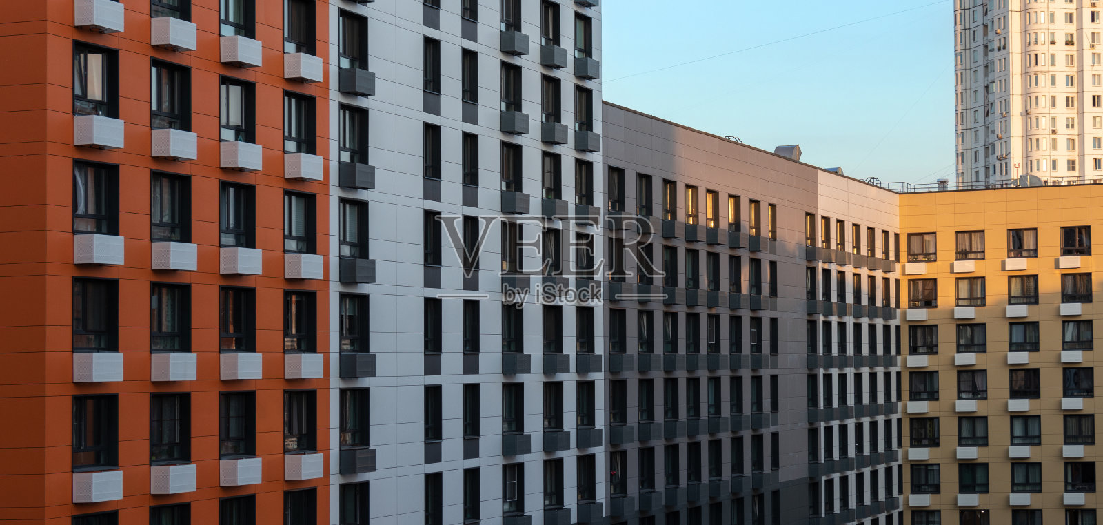 夕阳下多层拐角公寓楼的彩色立面。鸟瞰图照片摄影图片