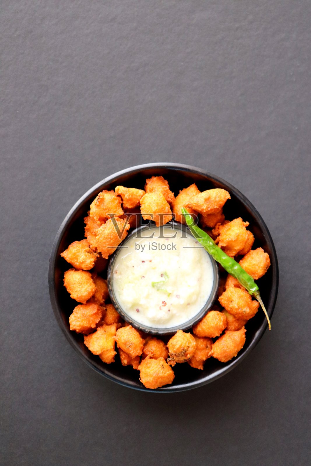 Moong和混合Dal Vada, ram laddoo, bhajias, Moongode，帕德或油炸饼，与油炸辣椒，凝乳和黄瓜酸辣酱或拉伊塔。在黑暗的背景下享用。有选择性的重点。与复制空间。照片摄影图片