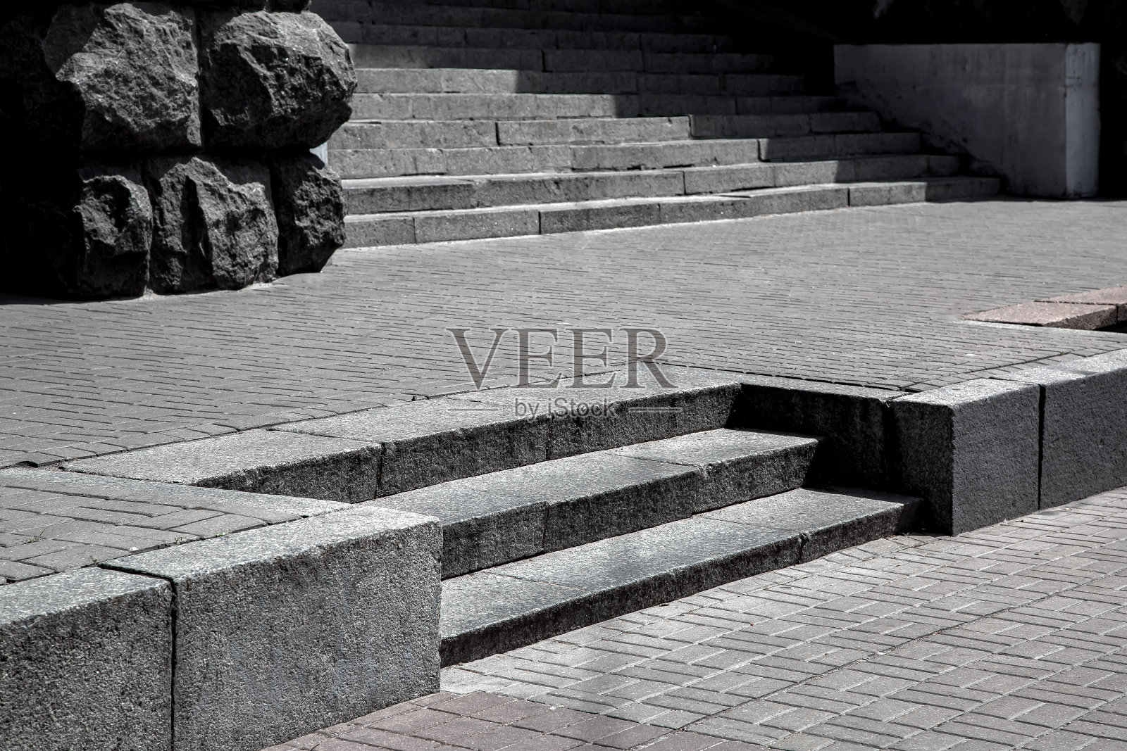 灰色花岗岩台阶中间的石瓦铺装砖花纹，城市景观与人行道附近的建筑和楼梯在阳光明媚的日子，楼面视野，无人。照片摄影图片