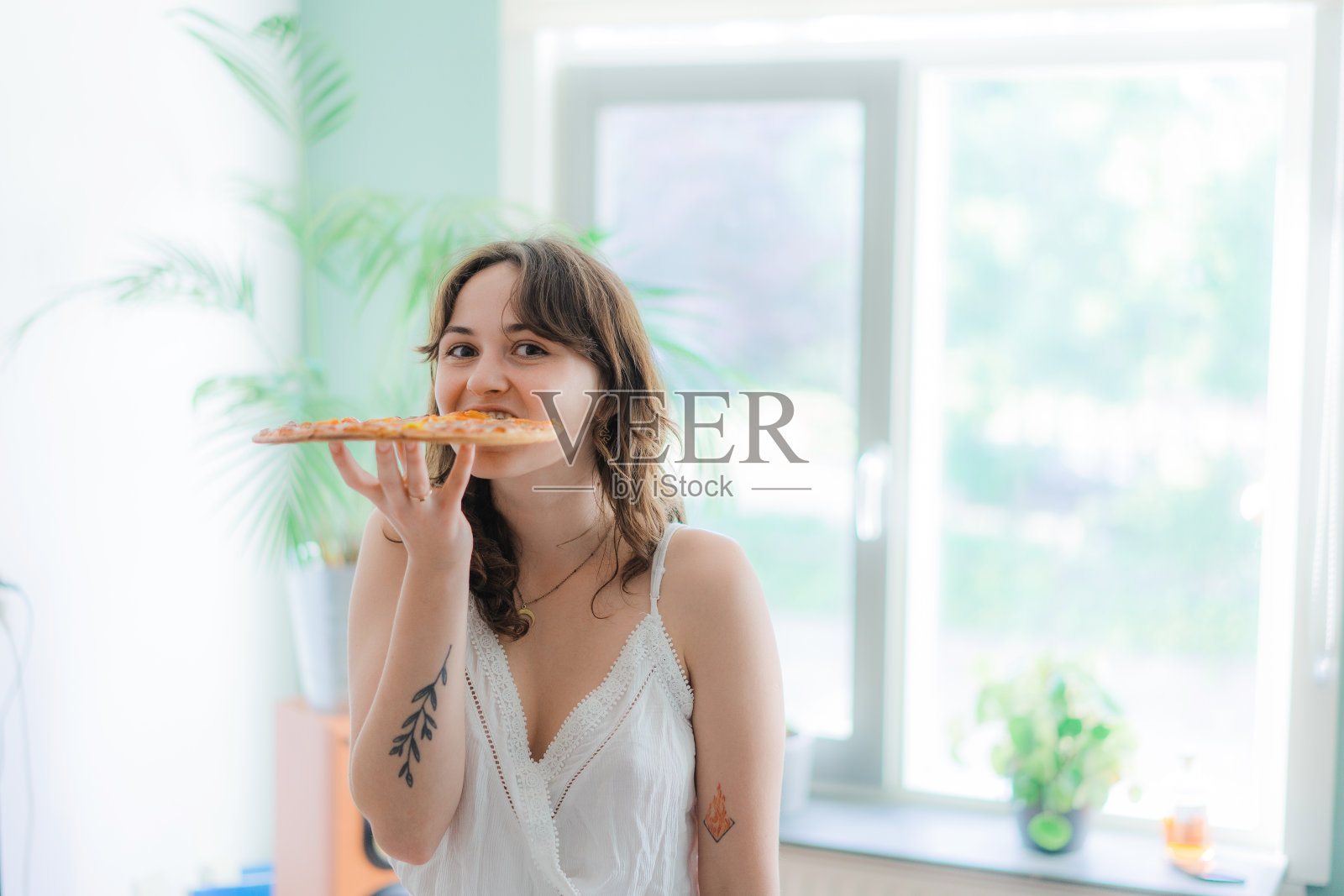 女人在家跳舞，吃整个披萨照片摄影图片