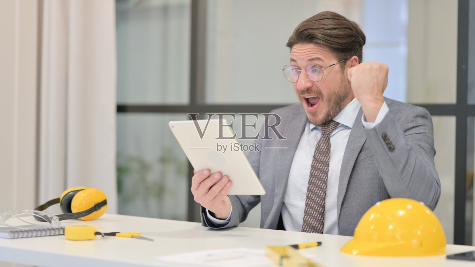 中年工程师在办公室用平板电脑庆祝成功照片摄影图片