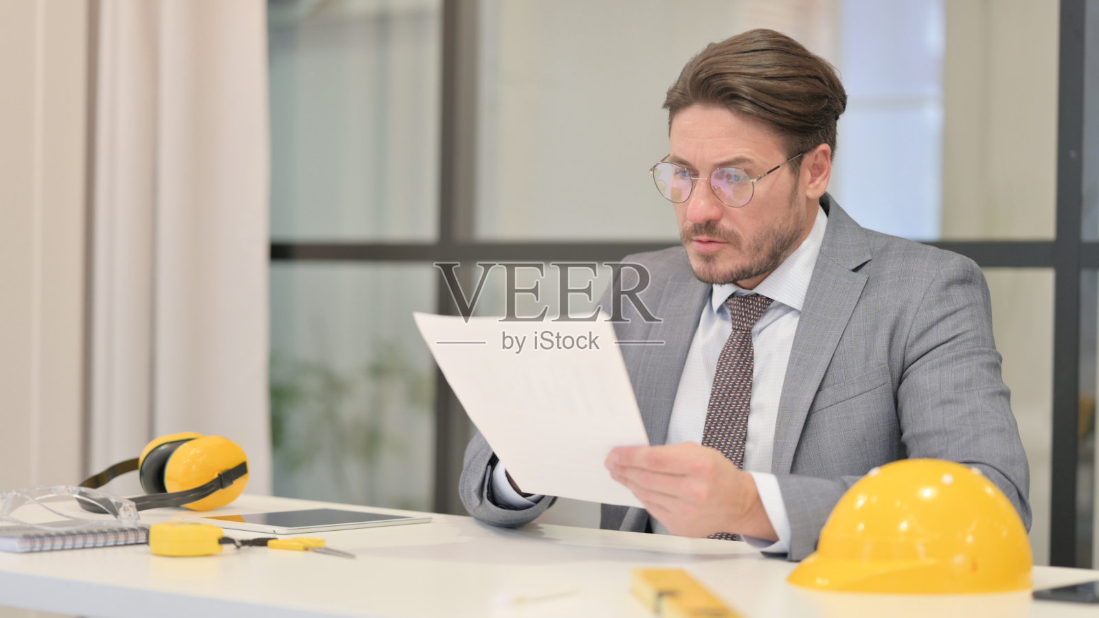 中年工程师坐在办公室里读报告照片摄影图片