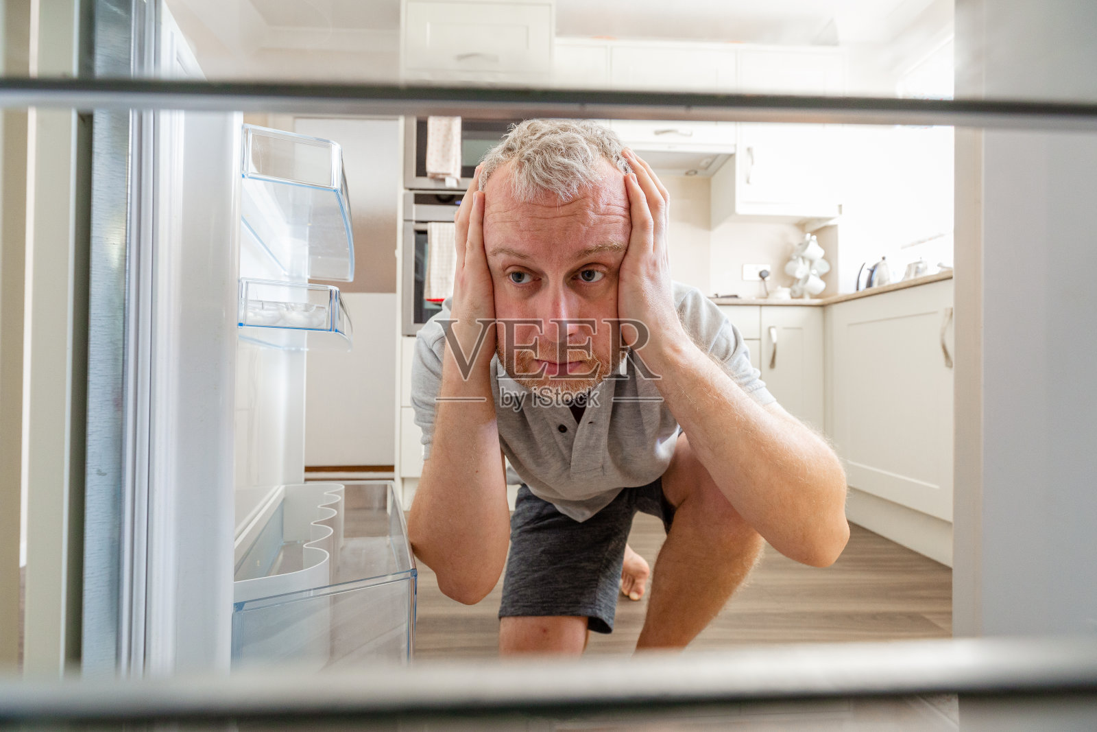 饥饿的人向空冰箱里张望照片摄影图片