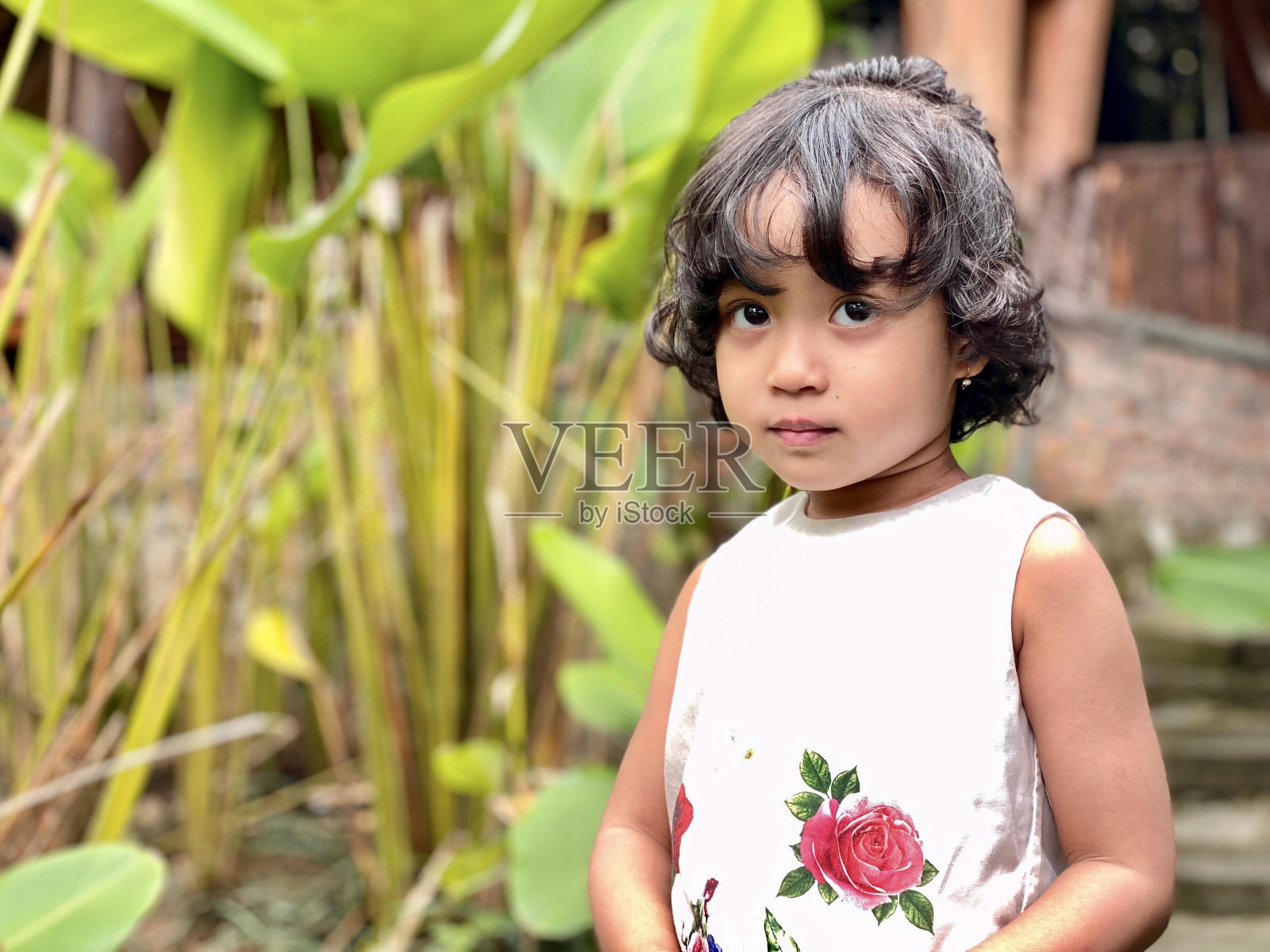 可爱的亚洲孩子的肖像穿着白色连衣裙户外树叶的背景照片摄影图片