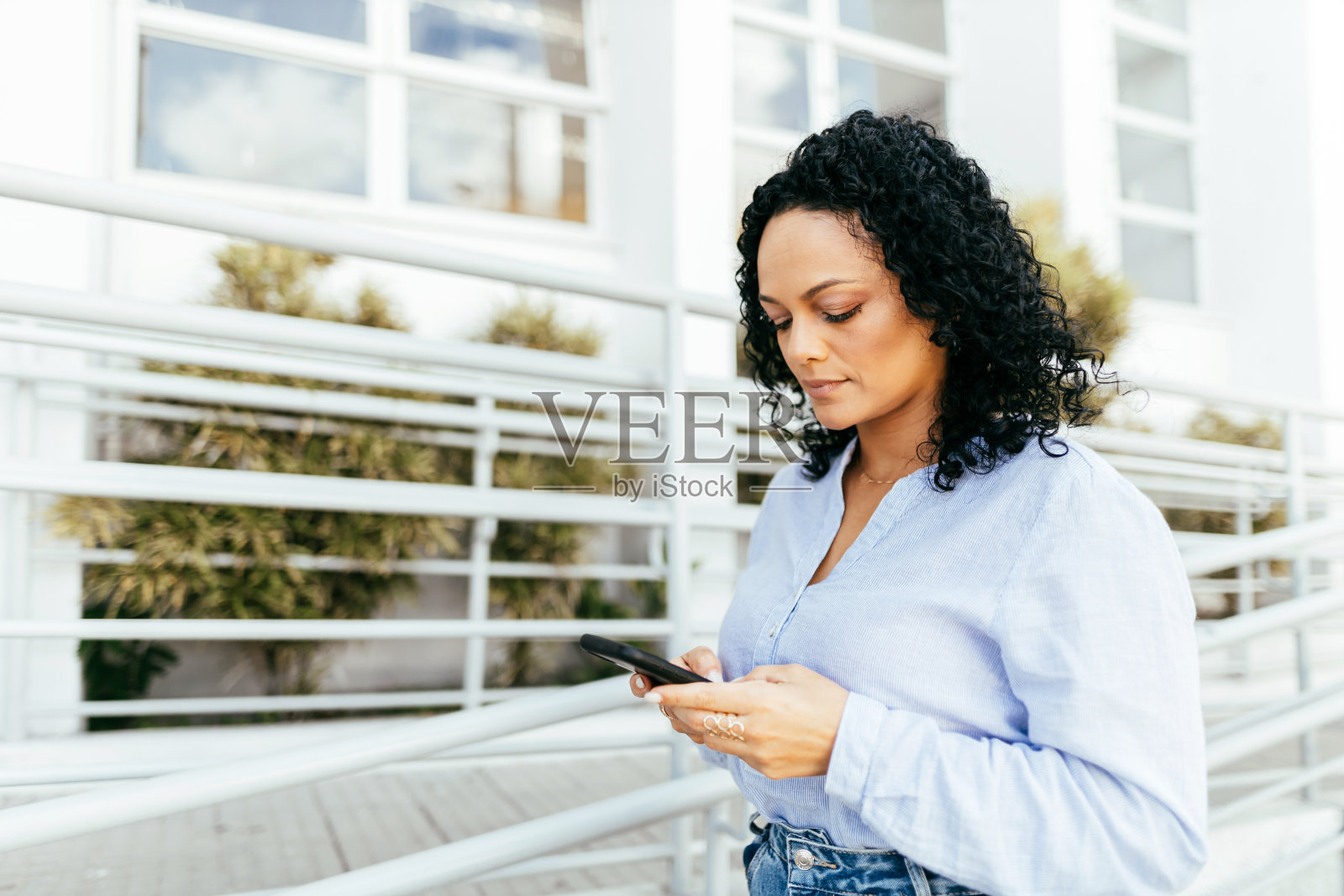 在城市里使用智能手机的女商人。照片摄影图片