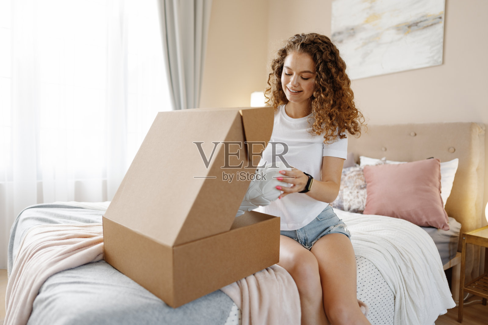 快乐的年轻女子在卧室打开包裹照片摄影图片