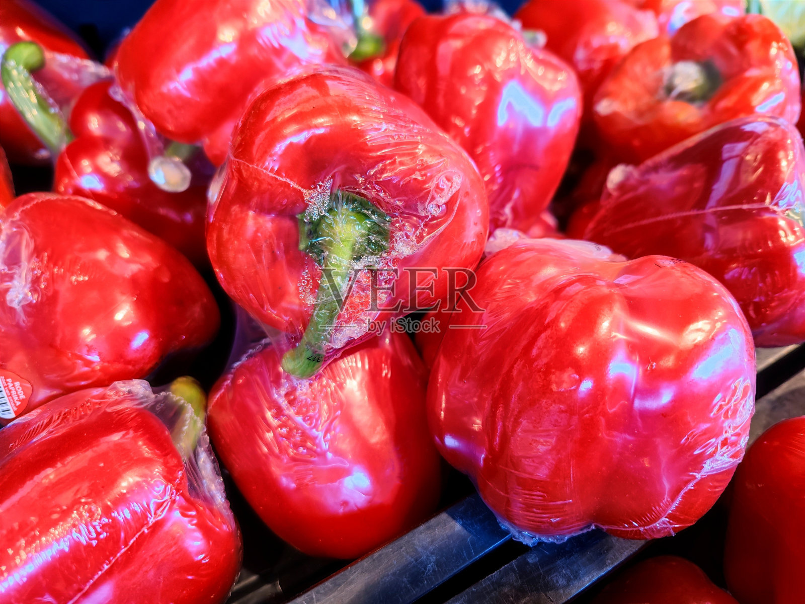 超市货架上一堆用塑料包装的美味新鲜红灯笼椒的特写照片摄影图片