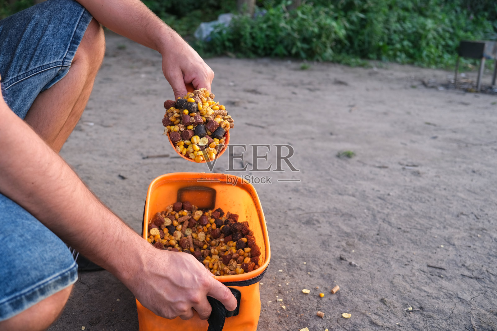 渔夫将鱼饵从玉米中混合放入桶中。照片摄影图片