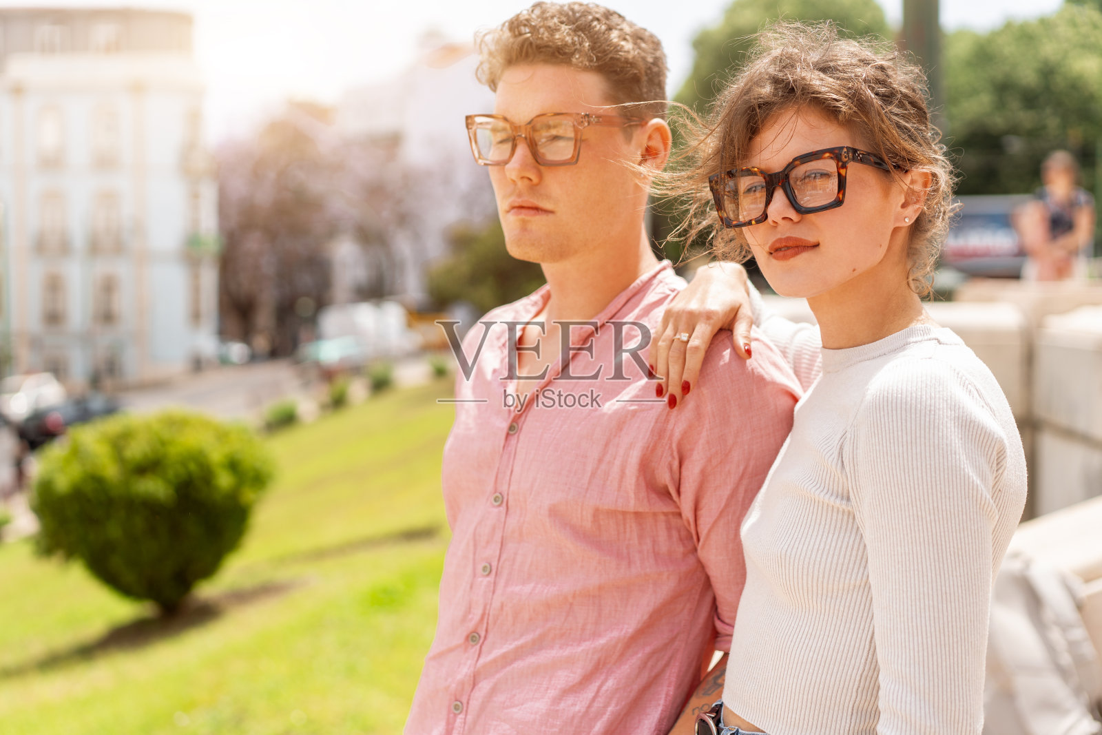 年轻漂亮的时髦夫妇戴着太阳镜恋爱走在老城街上照片摄影图片