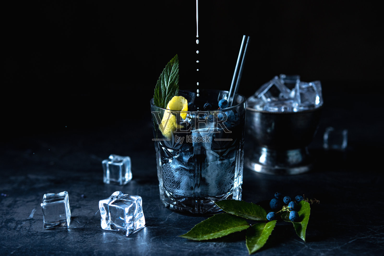 黑色鸡尾酒与柠檬和冰在黑色的背景。照片摄影图片