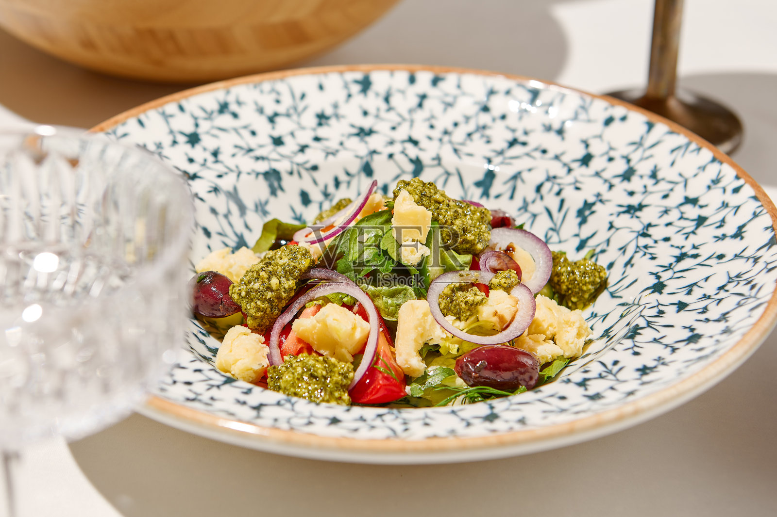 传统的意大利食物——用西红柿，洋葱圈和油炸面包丁做成的panzanella沙拉。夏日菜单白色餐桌上的潘萨内拉沙拉。在阳光明媚的日子里搭配番茄沙拉和玻璃杯。照片摄影图片