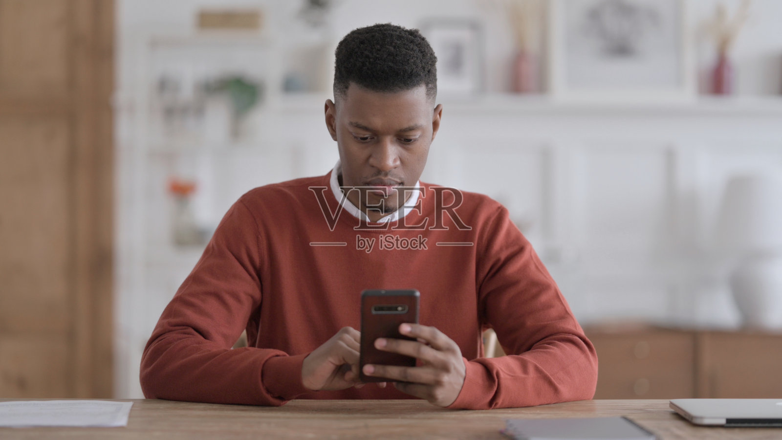 迷人的非洲男人在办公室里使用智能手机照片摄影图片