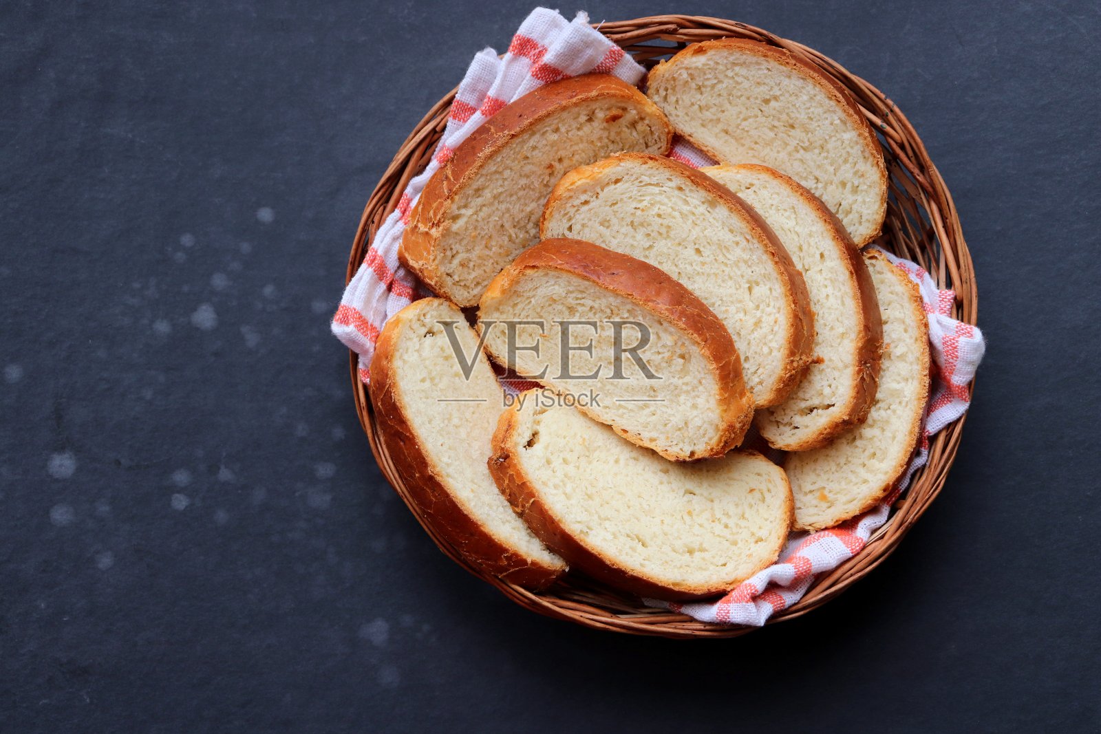 新鲜出炉的自制白面包片放在木制篮子里，放在质朴的黑色木桌上。早餐面包放在托盘里，上面有鲜花，还有复印空间。面包卷。奶油水果蛋白饼。孟买Ladi奶油水果蛋白饼照片摄影图片