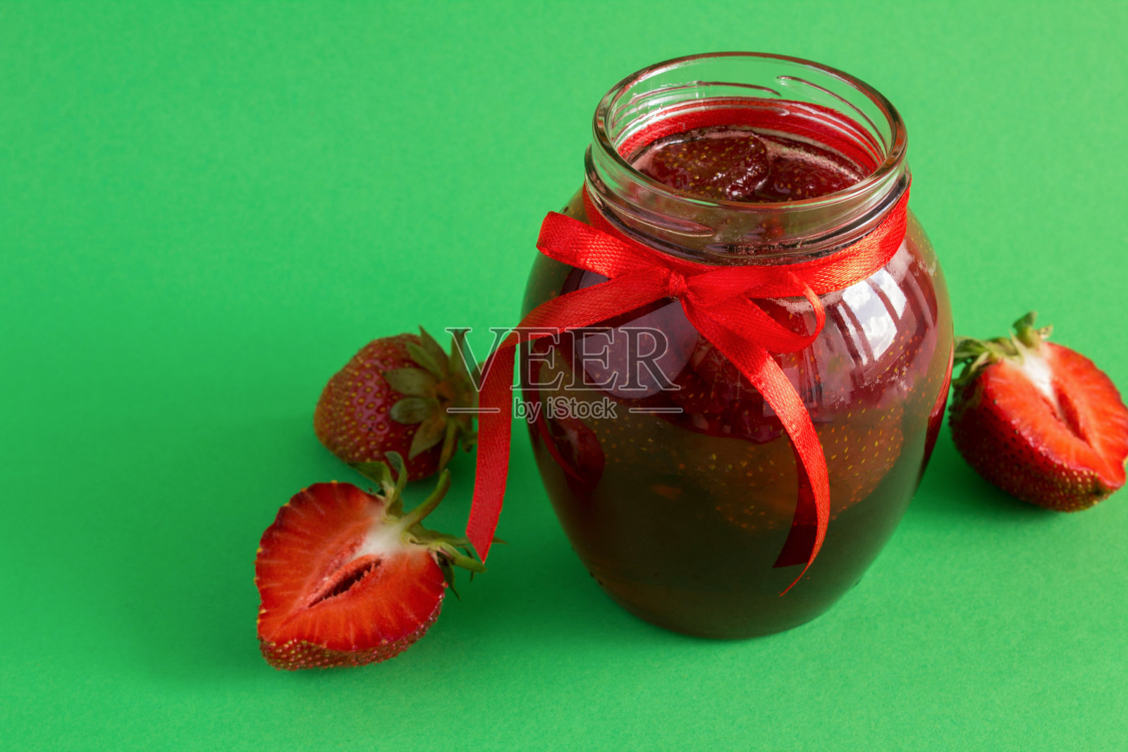 草莓酱在绿色背景的玻璃罐里。特写镜头。副本的空间。照片摄影图片