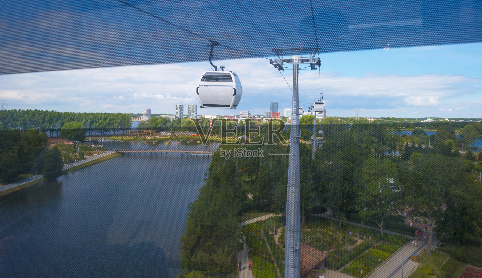 夏天，在蓝色明亮的天空中，从公园上空的缆车上看到城市的天际线照片摄影图片