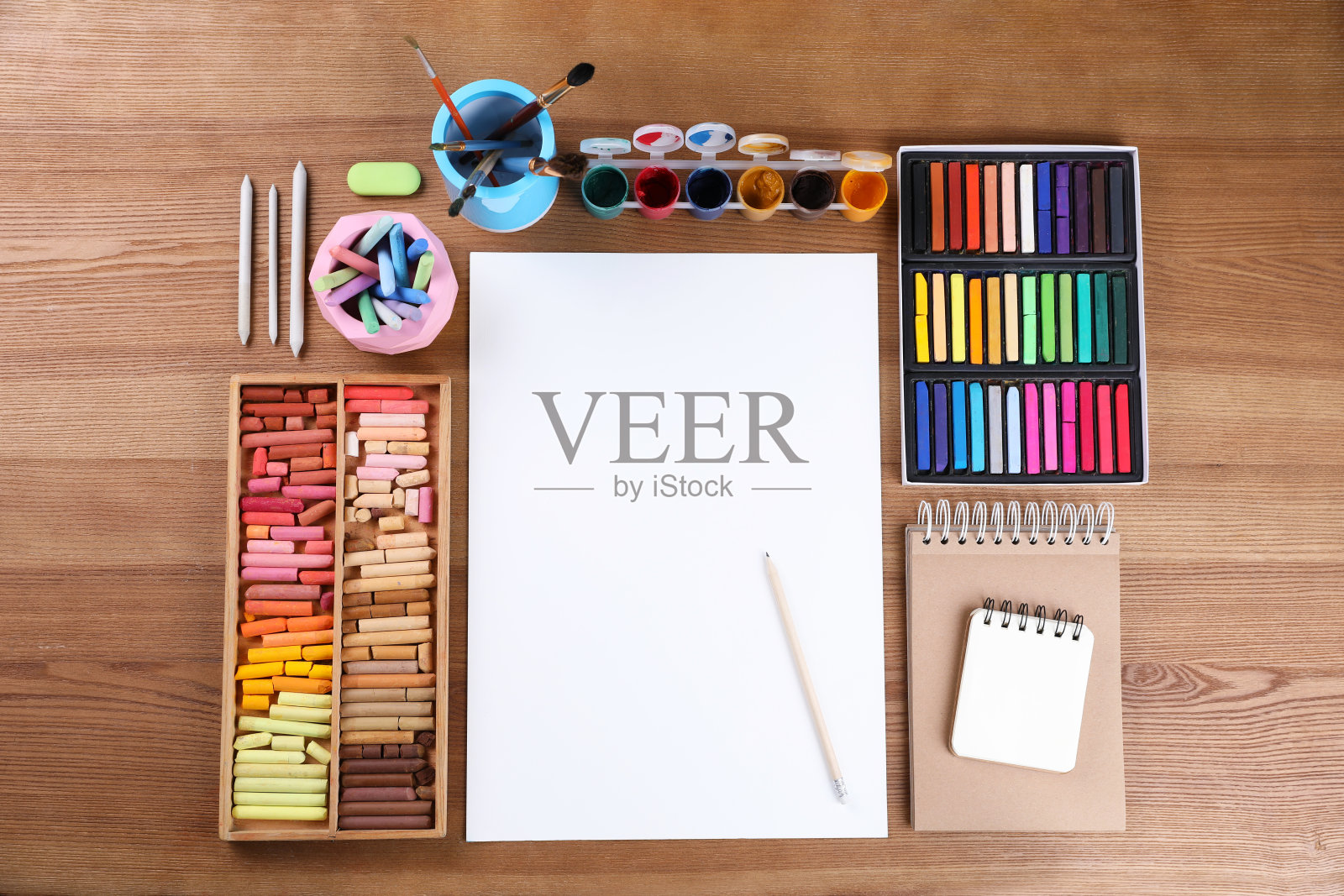 白纸、彩色粉笔和其他绘画工具放在木桌上，平铺。现代艺术家的工作场所照片摄影图片