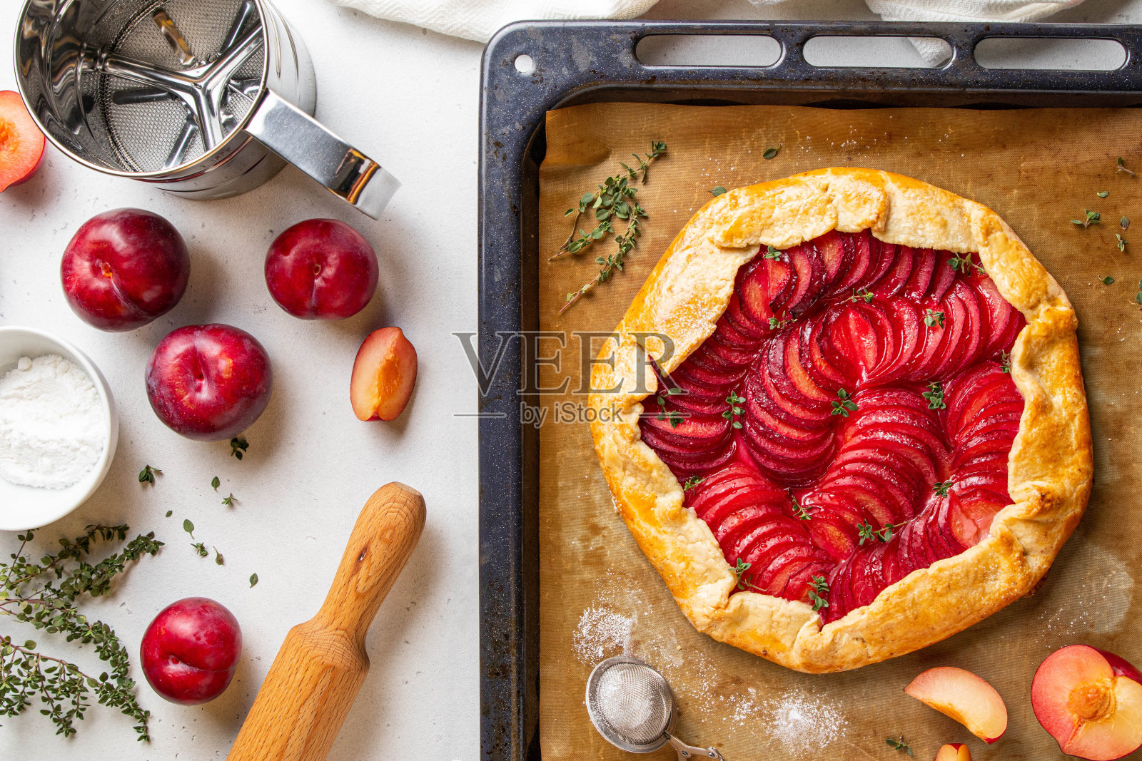 梅子加百里香烤盘，背景明亮。健康的自制水果派配李子。素食素食蛋糕。夏天的概念。前视图。照片摄影图片