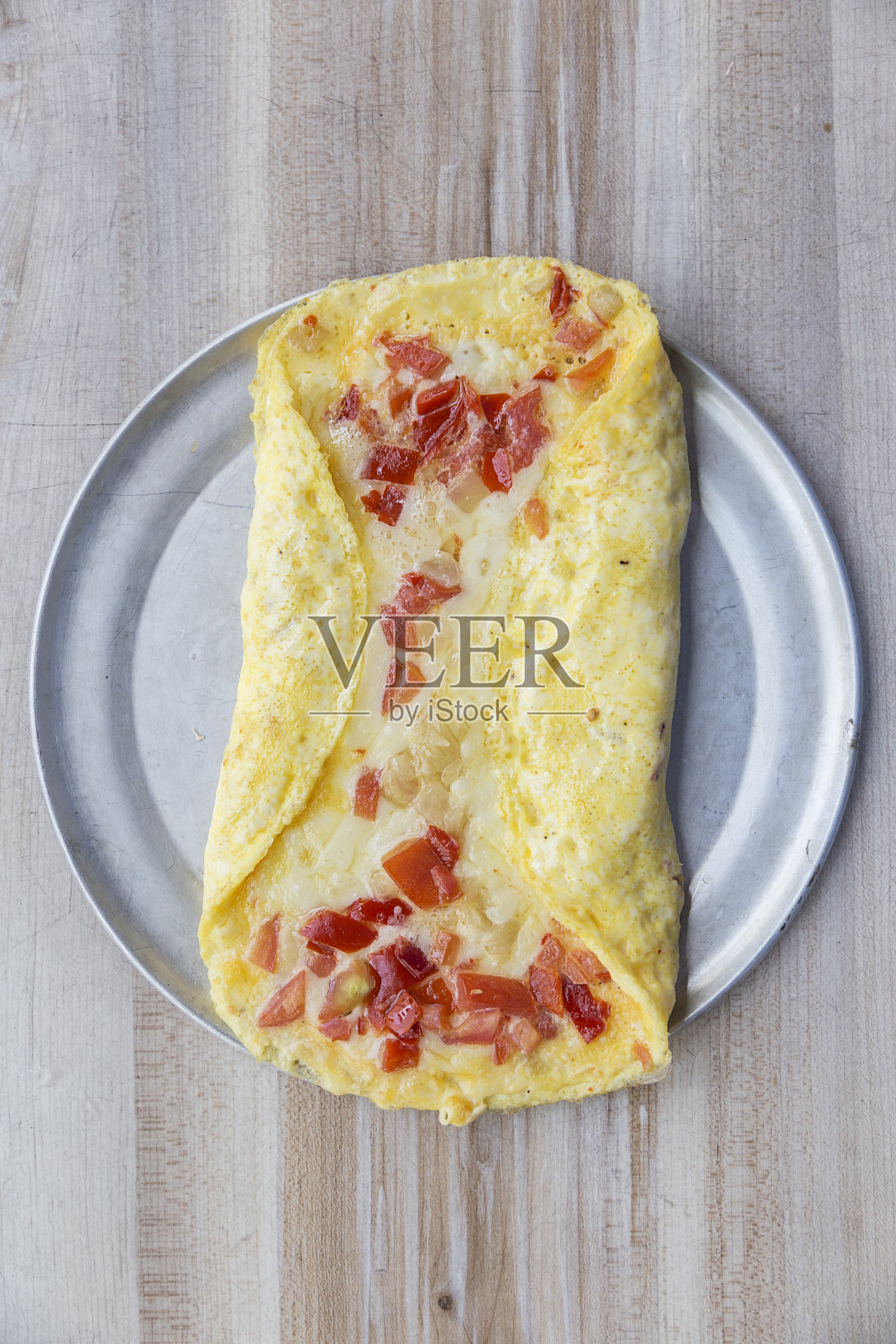 有芝士和番茄的煎蛋卷放在木桌上的银盘子里。早餐照片摄影图片