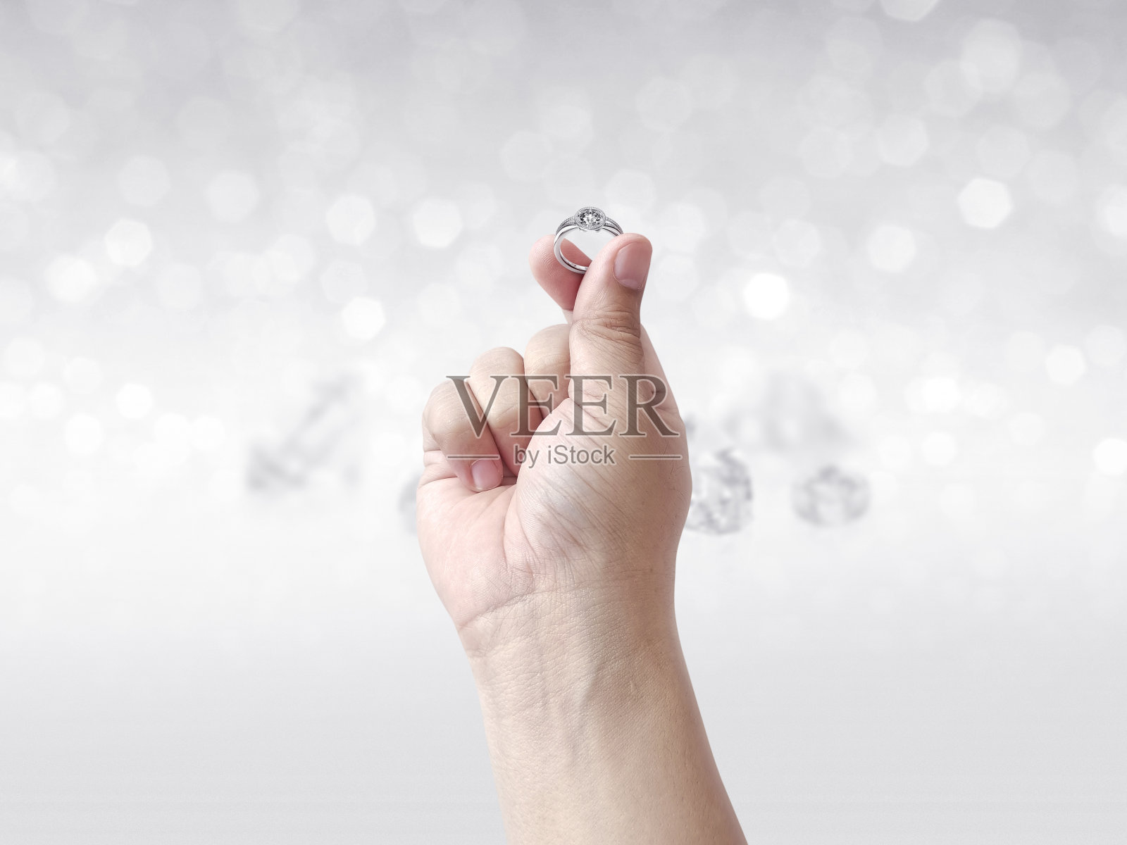 手握钻石戒指在闪光的背景照片摄影图片