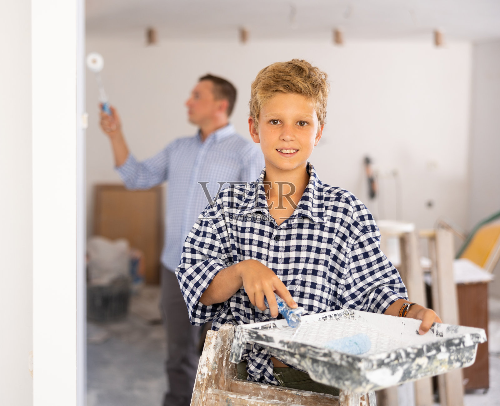 积极的年轻男孩肖像与油漆辊照片摄影图片