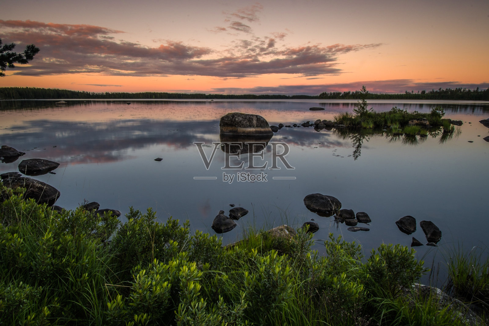 瑞典南部，日落时湖面上的壮观景色，前景是岩石照片摄影图片